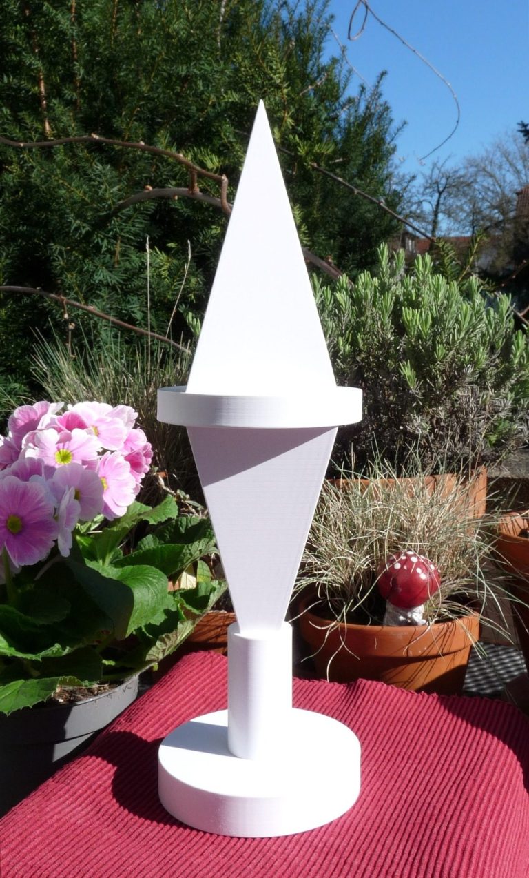 Meditationspyramide Goldener Schnitt Energiepyramide Meditationspyramide aus Kunstoff auf der Terasse stehend mit blühenden Sträuchern im Hintergrund.