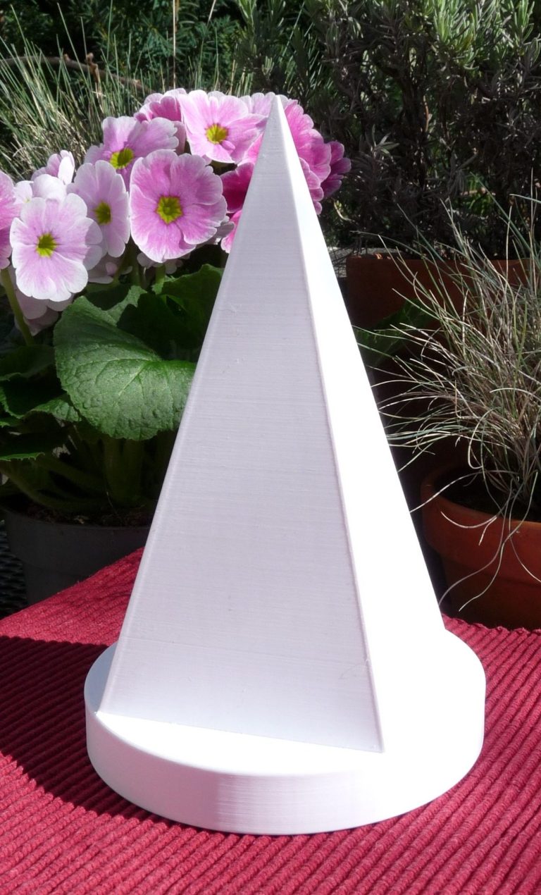 Pyramide Goldener Schnitt Weiße Pyramide Goldener Schnitt auf rundem Podest dahinter blühende Blumen