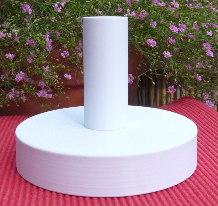 Halter für die Podestpyramide Ein Halter für eine Podestpyramide auf einem Gartentisch mit blühenden Blumen.